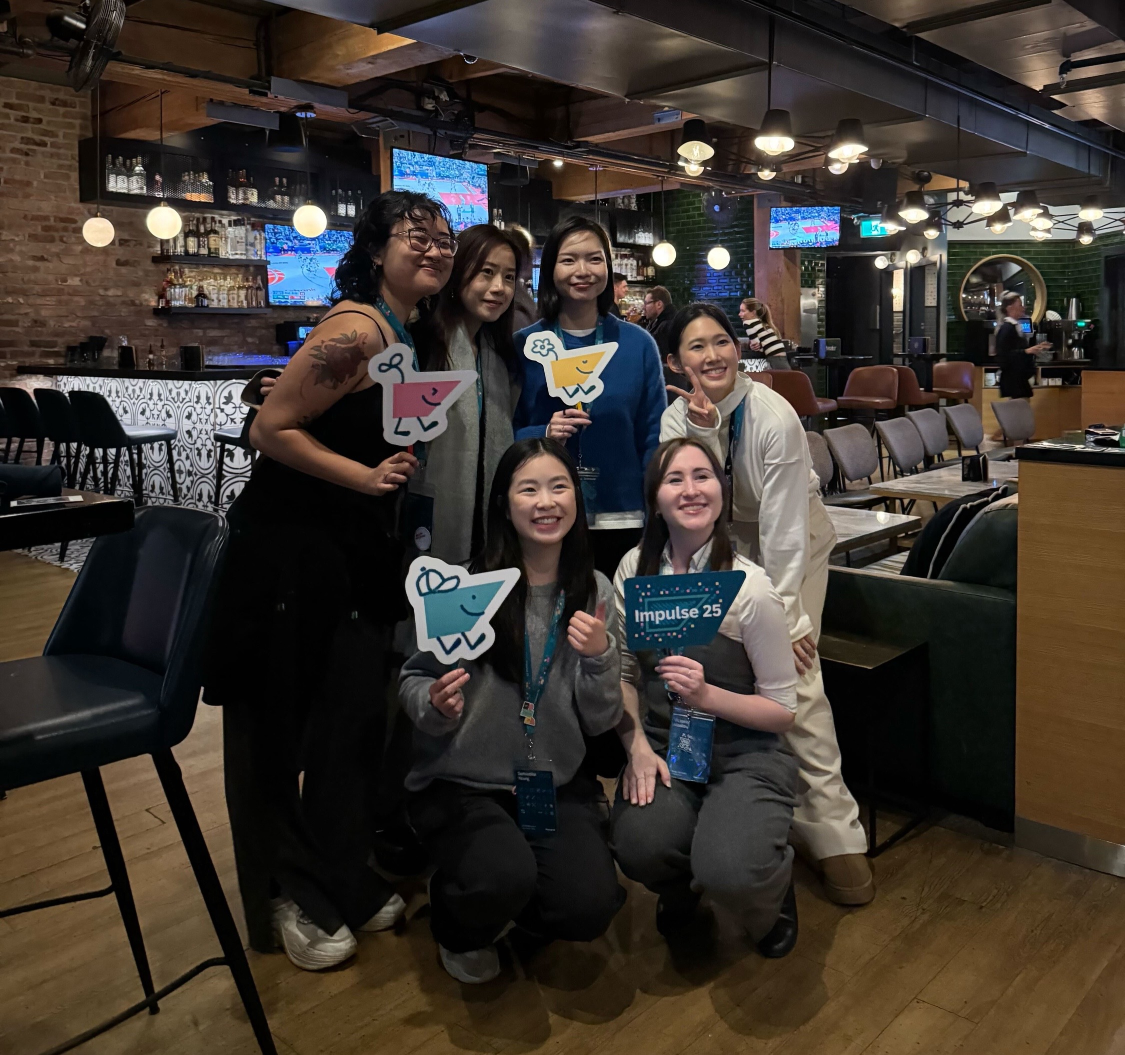 A group of seven people smiling and holding colorful cartoon cutouts